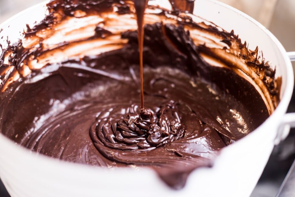 Melted dark chocolate being stirred in a white bowl — bloomed chocolate melts down beautifully for baking