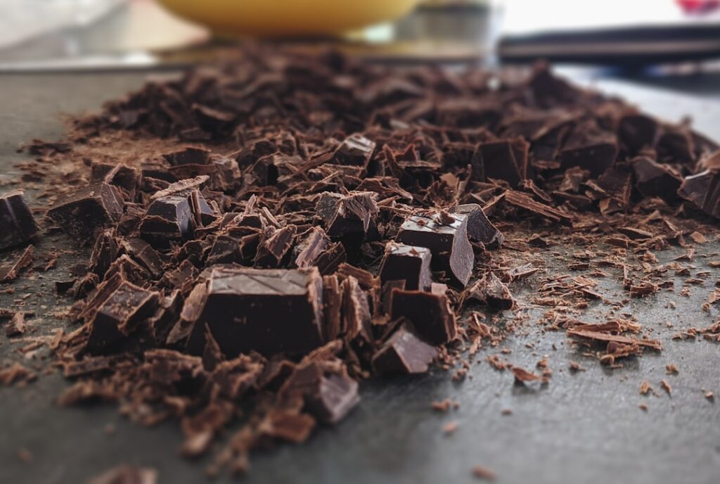 Chopped dark chocolate pieces and shavings scattered on a kitchen counter, ready for melting