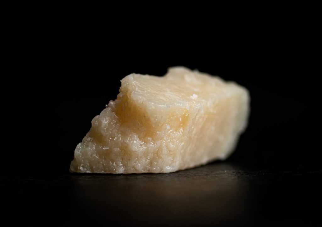 A wedge of aged parmesan cheese on a dark background, illustrating a naturally glutamate-rich food