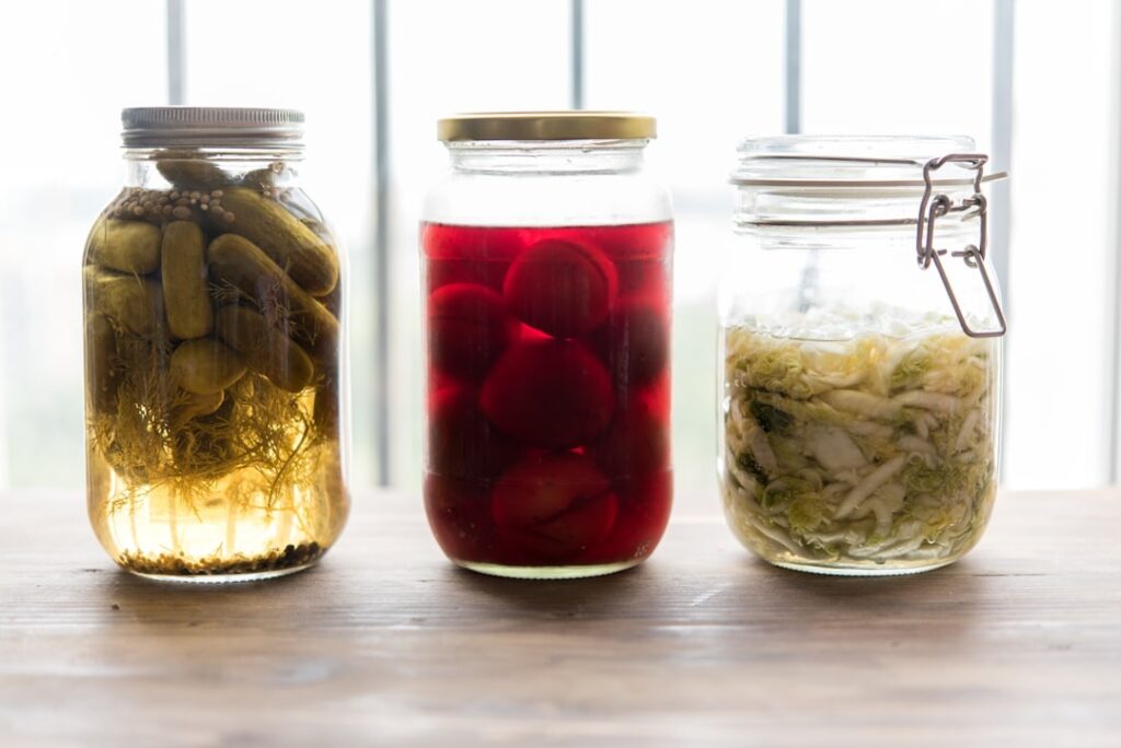 Three glass jars of fermented and pickled foods representing lactic acid fermentation and food preservation science