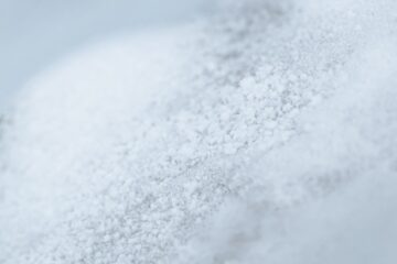 Close-up macro photograph of white crystalline powder resembling MSG or sodium salt crystals