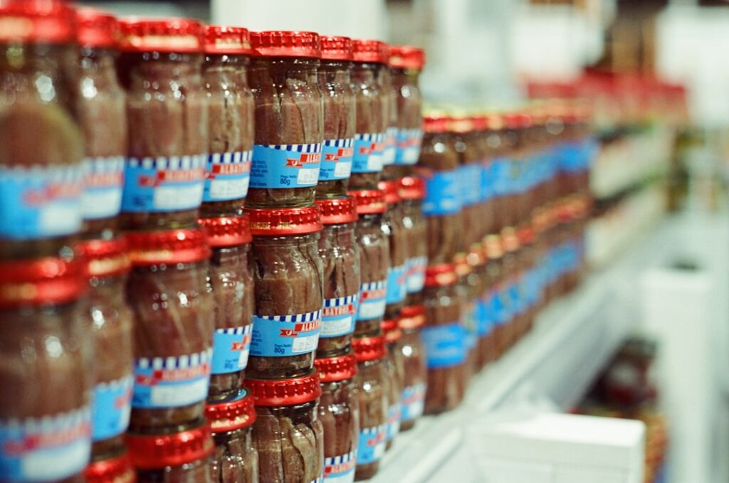 Rows of labeled glass jars receding along a grocery store shelf, illustrating how products are stocked
